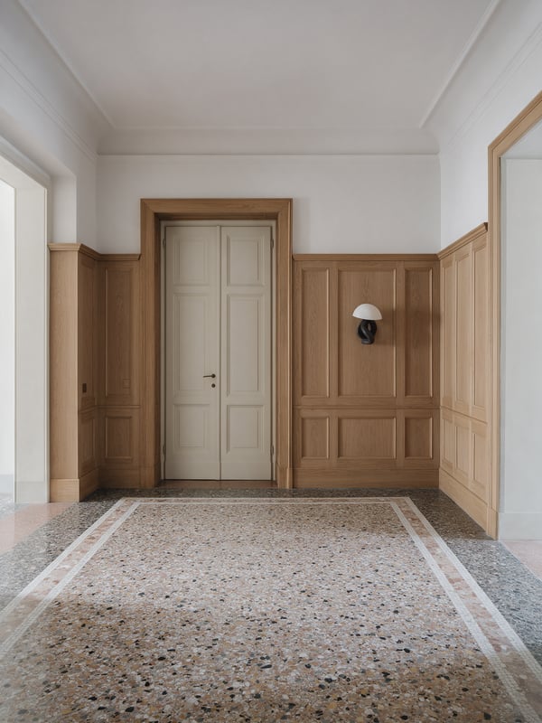 Recibidor con puertas dobles, suelo de terrazo restaurado y paneles de roble